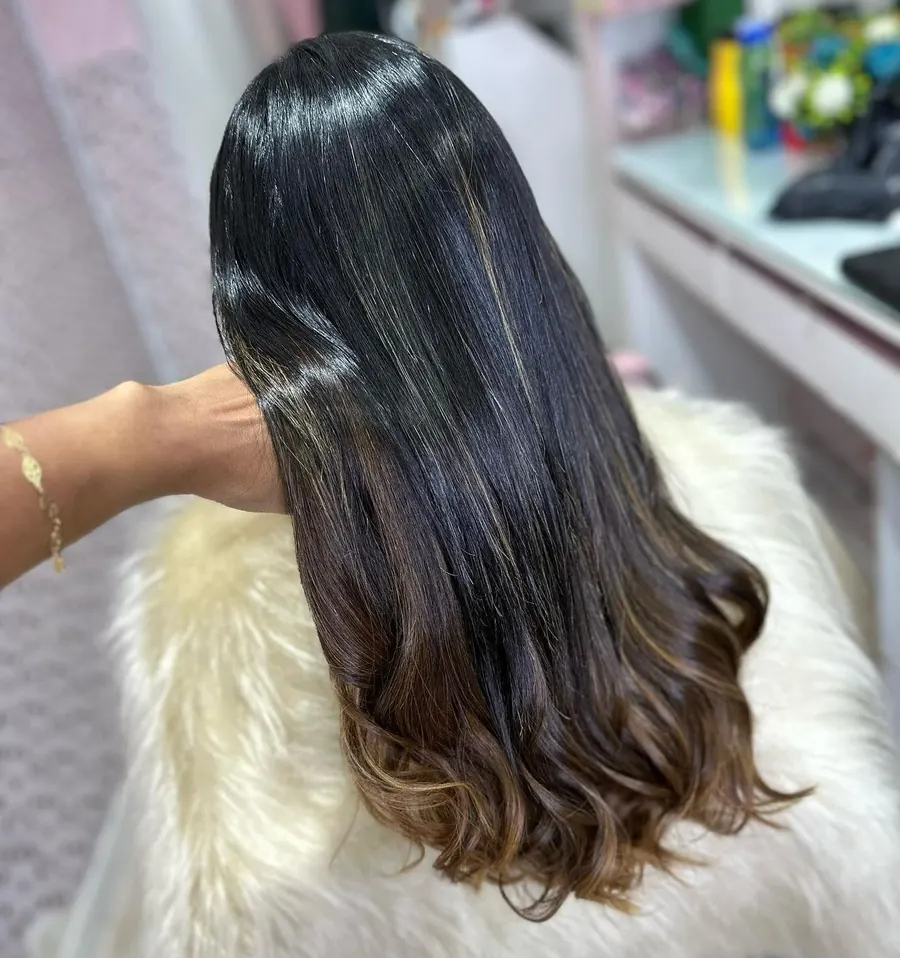 Cabelo preto longo com pontas em castanho e ondas, sobre uma manta clara